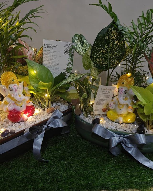A pair of festive planters built around Ganesh figures, finished with ribbon and small lights.
